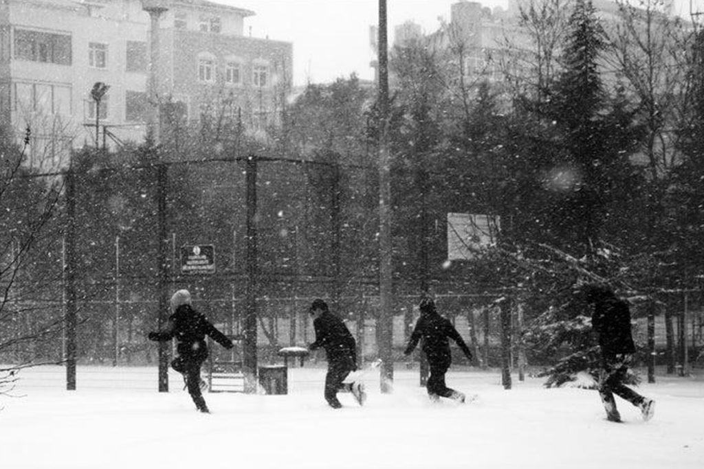 una foto in bianco e nero di quattro bambini che corrono e giocano nella neve