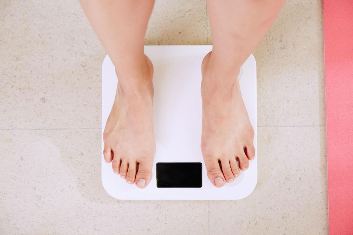 Persona intenta a pesarsi sulla bilancia per paura di essere sovrappeso