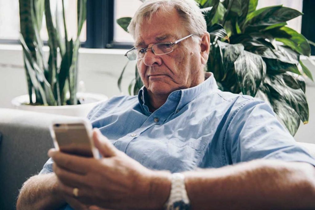 Un anziano vive un momento di solitudine affidandosi al suo telefono per paura di invecchiare