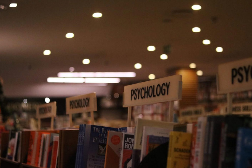 Scaffali di una libreria con molti libri di psicologia di vari autori ordinati su più piani