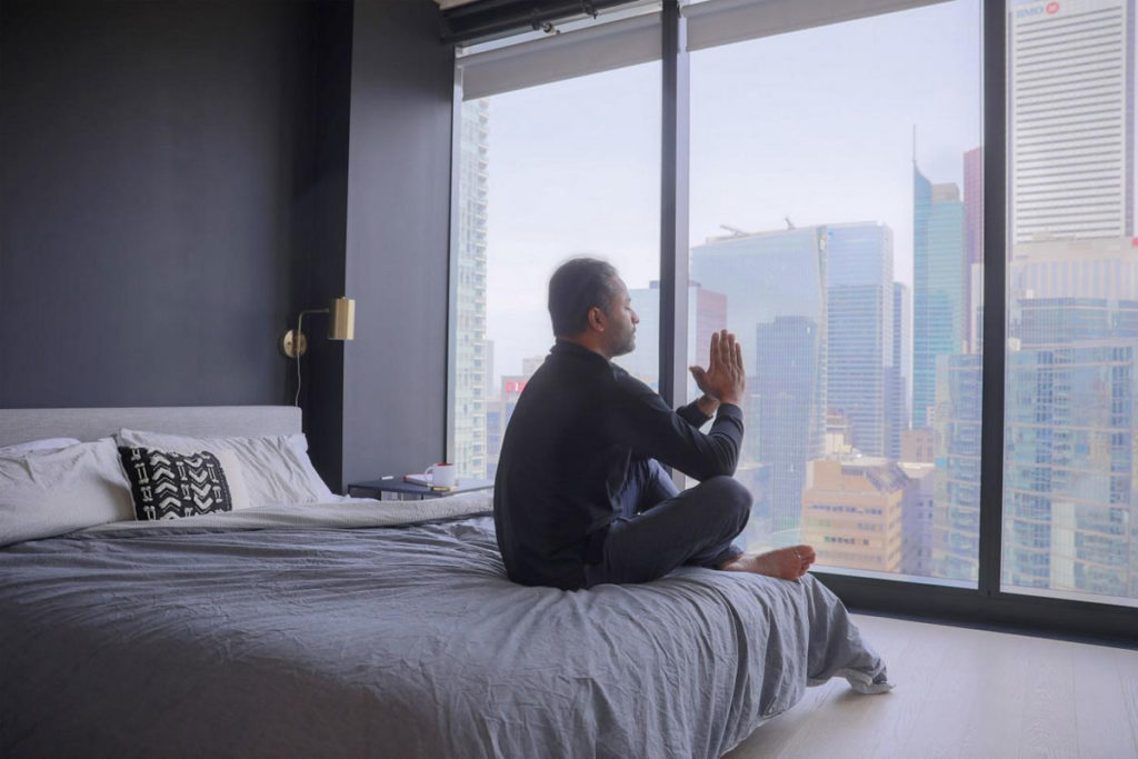 Un uomo medita sul letto praticando gratitudine per quello che ha conquistato nella vita