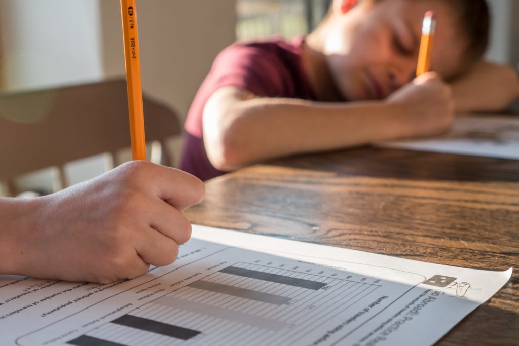 due bambini che scrivono appoggiati a un tavolo