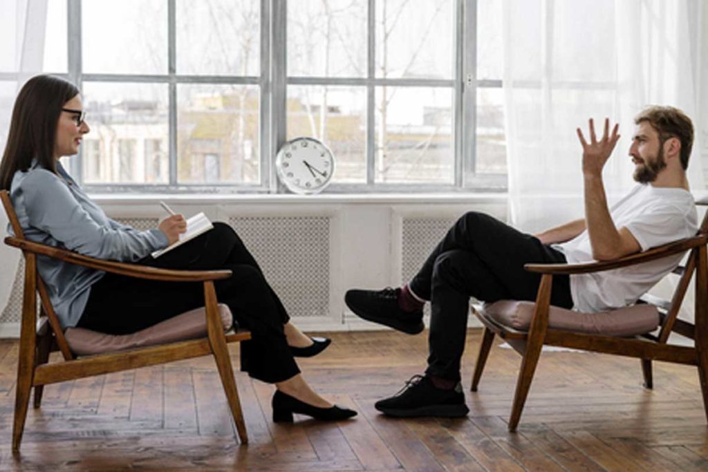 Coppia composta da un uomo e una donna seduti in ufficio che parlano