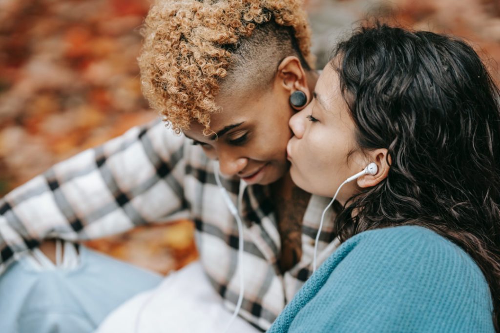 due amanti si baciano mentre ascoltano musica in un parco ricoperto di foglie durante l'autunno