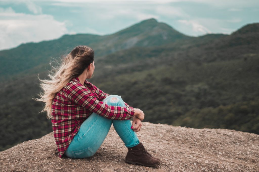 una donna seduta su una roccia ammira il panorama naturale e le montagne intorno a lei