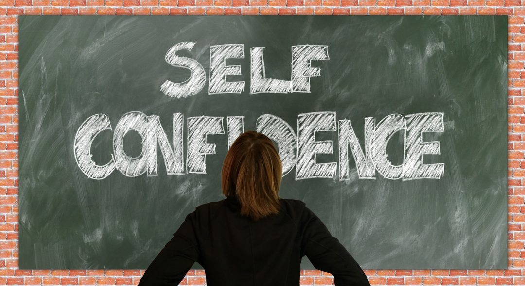 una donna legge la frase motivazionale Self Confidence su una lavagna