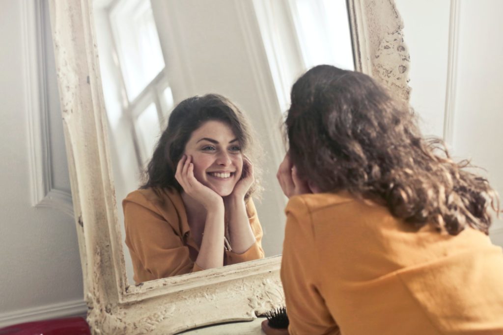 Donna sorride mentre si guarda allo specchio