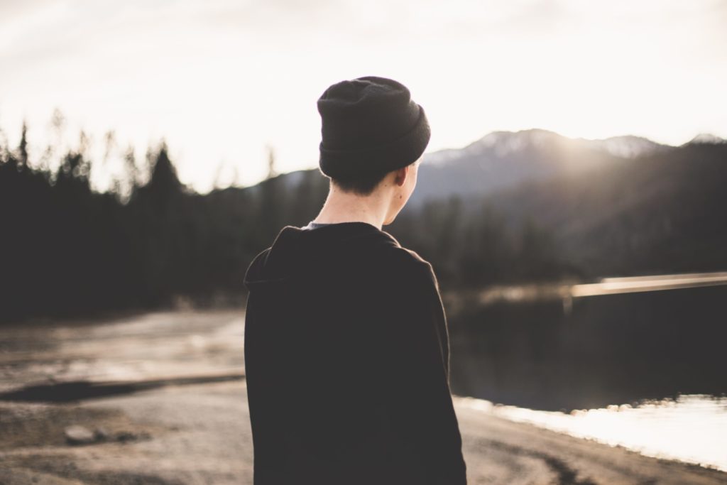 un ragazzo osserva il panorama da solo di fronte a un lago