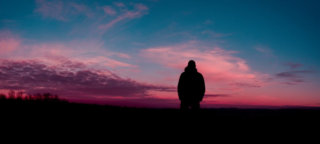 uomo guarda l'alba da solo in un paesaggio naturale