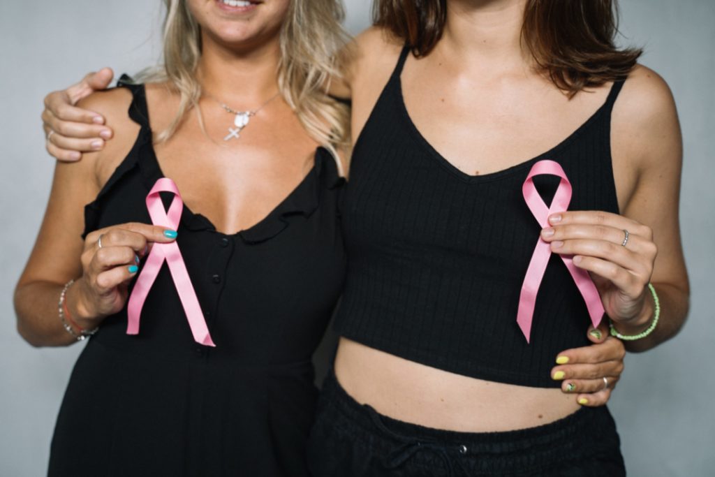 due donne con il fiocco rosa, simbolo di prevenzione e cura del tumore al seno