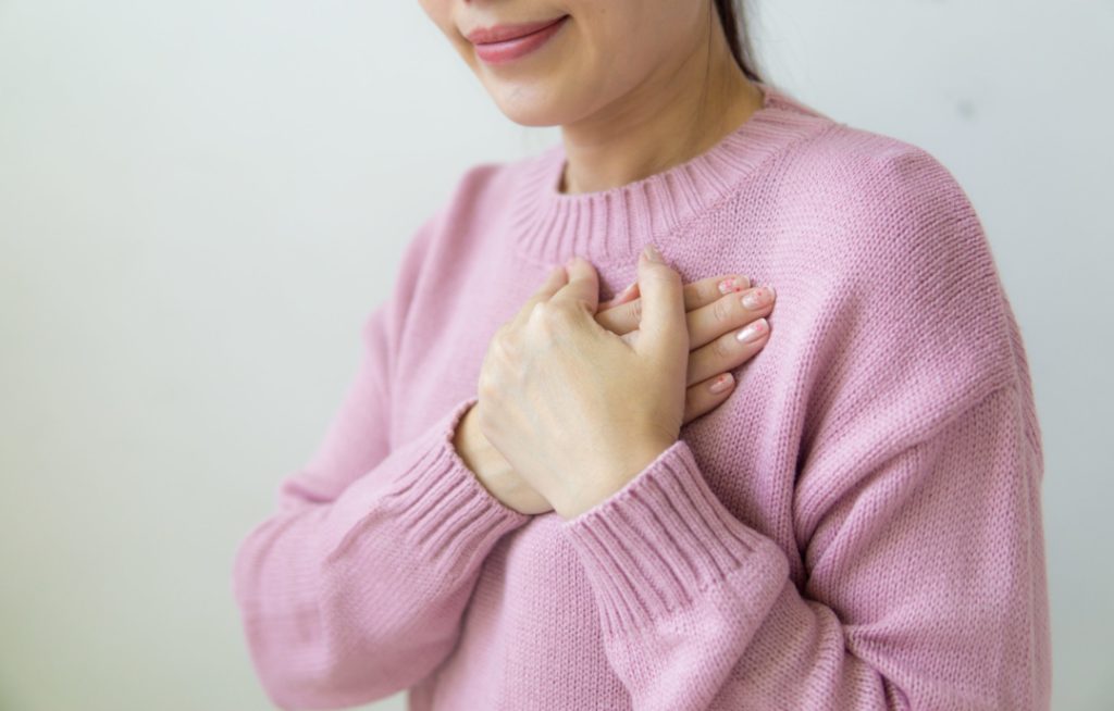 una donna vestita di rosa mette le mani sul petto in segno di gratitudine