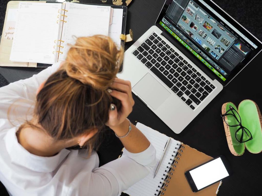 donna stressata con la testa tra le mani mentre lavora al pc