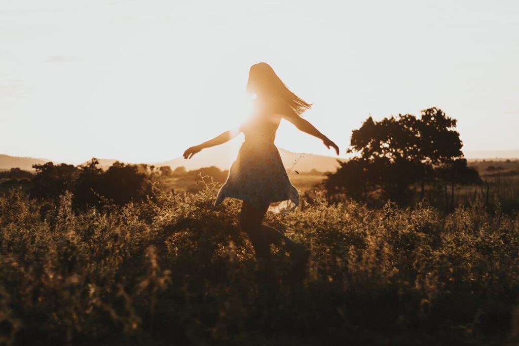 donna cammina libera in un campo durante il tramonto