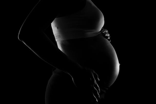 foto in bianco e nera della pancia di una donna incinta