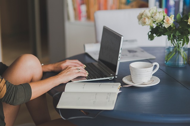 una ragazza studia al pc portatile con un libro e una tazza di caffè