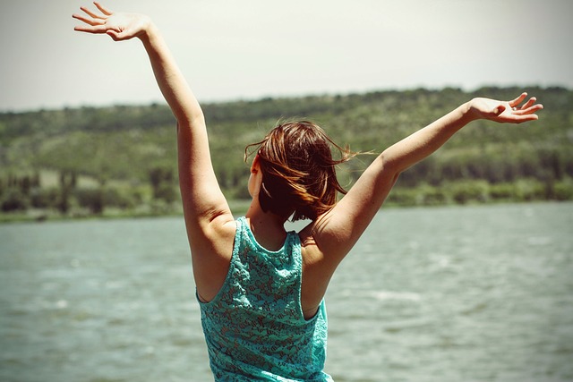 donna alza le braccia al cielo felice in un paesaggio naturale
