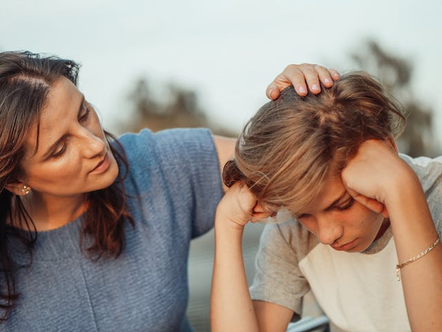 mamma accarezza il figlio che sembra preoccupato