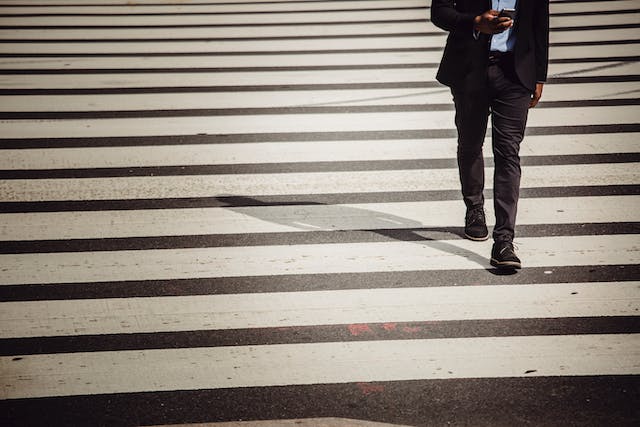 uomo attraversa la strada mentre guarda lo smartphone