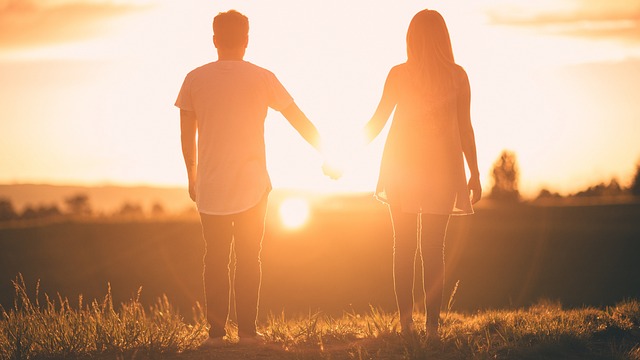 uomo e donna si tengono per mano al tramonto
