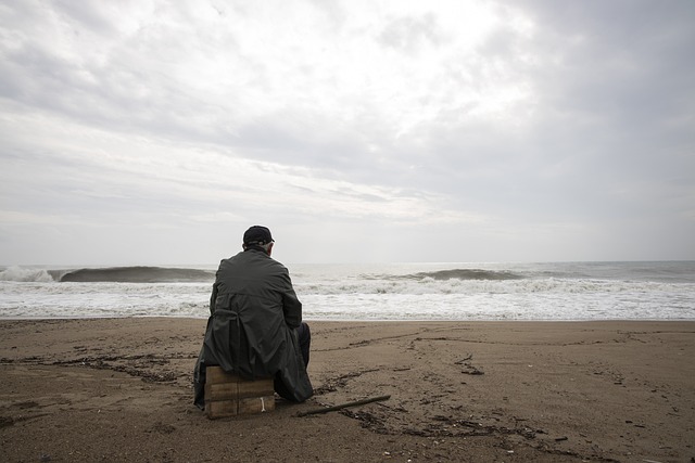 uomo seduto da solo sulla spiaggia