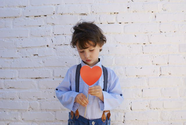 bambino con un cartoncino a forma di cuore in mano