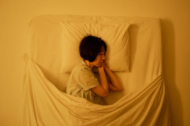 Donna stesa a letto che fissa il vuoto