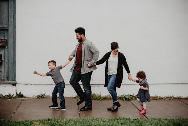 genitori con due figli camminano tenendosi per mano