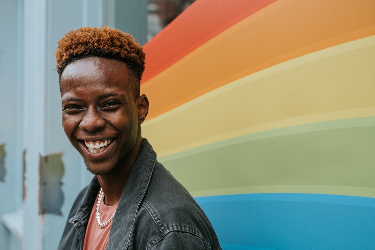 Gene gay: un ragazzo sorride di fronte a un arcobaleno dipinto