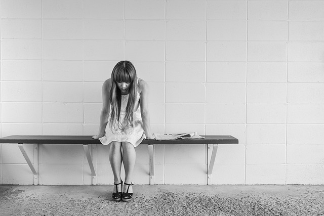 una ragazza da sola seduta su una panchina