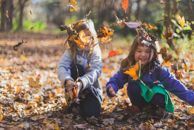 bambine che giocano con le foglie in un parco