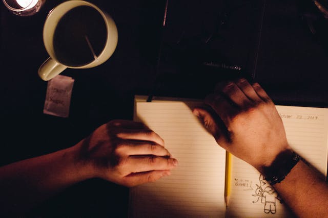 uomo che scrive un diario con tazza di tè